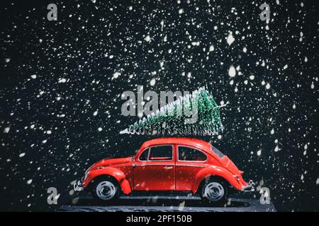 Red retro car with Christmas tree on roof during heavy snowfall Stock Photo