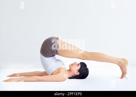 Athletic young woman doing twist stretching exercises on the floor