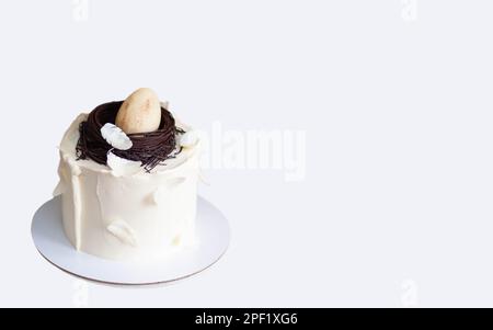 Elegant easter cake decorated with chocolate bird's nest, egg and feathers. White background with copy space. Horizontal orientation Stock Photo