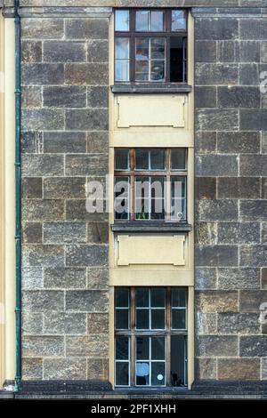 Three rectangular windows located vertically above each other on the facade of a building made of gray stone blocks. From the Windows of the world ser Stock Photo