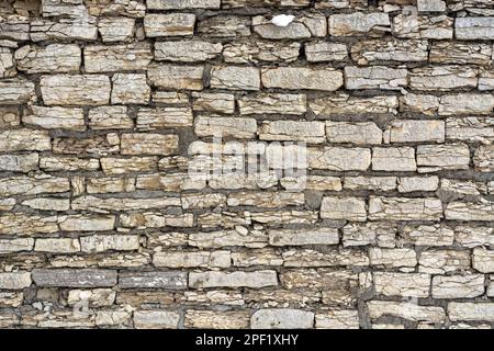Fragment of a wall made of old cracked stones in beige color for use as an abstract background and texture. Stock Photo