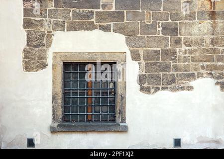 Square window with a metal grill against a partially plastered wall of stone blocks. From the Window of the World series. Stock Photo