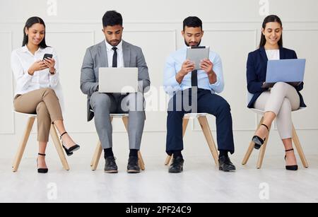 Group of diverse businesspeople waiting for interview and using technology. Team of young applicants sitting together. Professional candidates in line Stock Photo