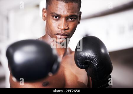 Put em up. An african american boxer with his gloves up standing in the ring. Stock Photo