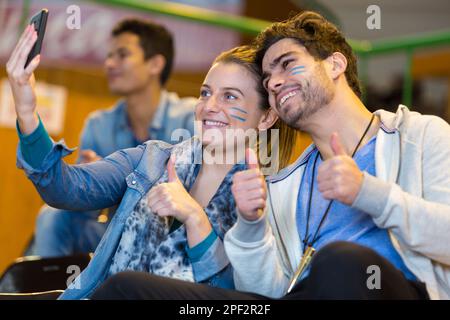 sports supporters taking selfie self-portrait with smartphone thumbs up Stock Photo