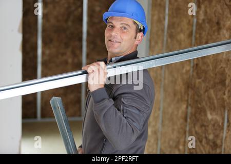 smiling construction worker carrying a metal bar Stock Photo