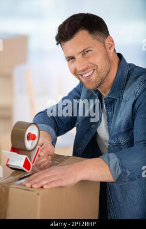 man using duct tape for packing stuff in box Stock Photo