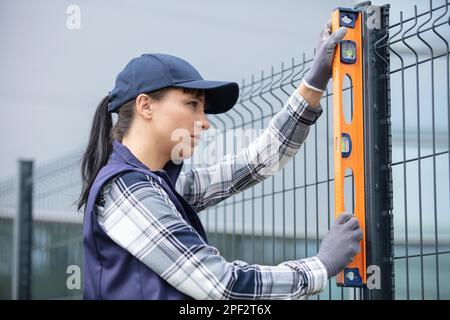 woman building fence - checking with spirit level Stock Photo