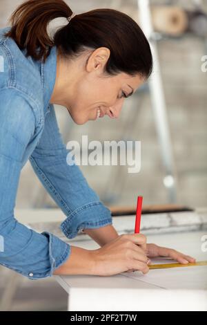 woman taking measurement of wallpaper in new home Stock Photo