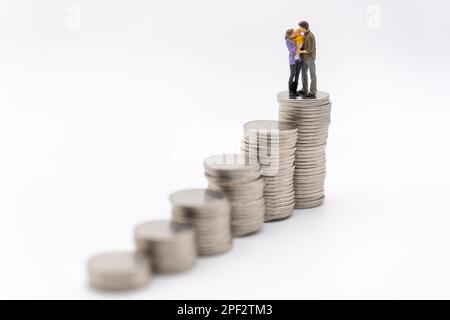Money, Financial, Business and Family concept, Miniature figures man, woman and child stand on top of stack of coins on white background. Stock Photo