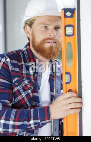 young male builder leveling a window Stock Photo