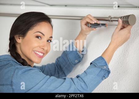 happy woman installing blinds with screwdriver Stock Photo