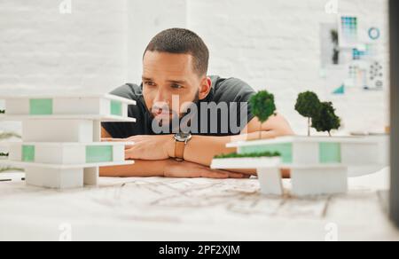 Focused architect looking at building model. Young businessman thinking about a building model. Handsome engineer working on a 3D building model Stock Photo