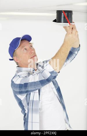 workman securing screws on ceiling vent Stock Photo