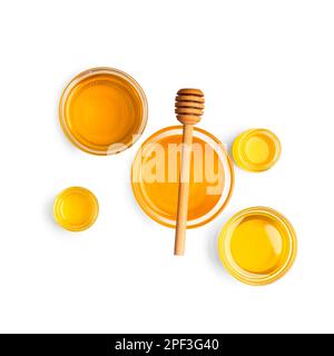 Creative composition of honey in glass bowls of different sizes and a wooden dipper on a white background top view. Stock Photo