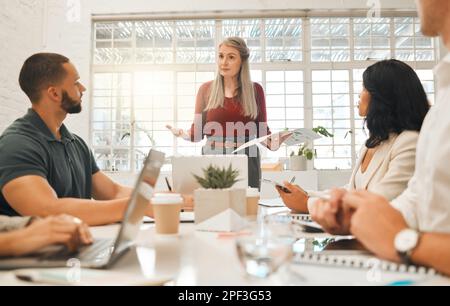 Mature boss asking staff a question in a meeting. Businesswoman collaborating in a meeting. Senior architect using a report during a meeting.Diverse Stock Photo