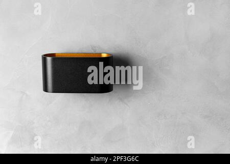 Modern black wall lamp on a gray texture wall with a place for the text. LED lamp on a gray background copy space. Stock Photo