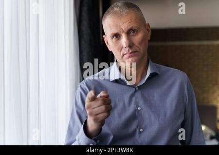 Confident businessman in a blue shirt pointing his index finger at the camera. The concept of people and gestures. Stock Photo