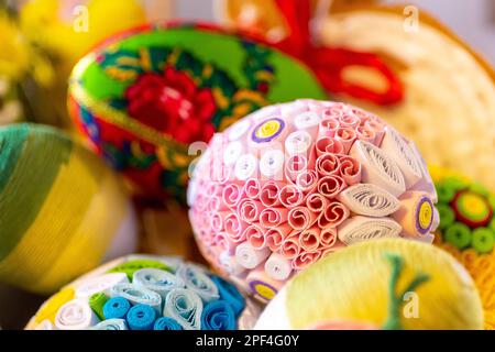 Colorful traditional Easter eggs with floral ornaments, origami decorations and crewel wool, close-up view. Stock Photo