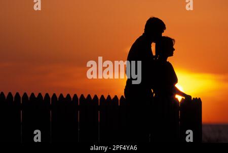 Silhouette of romantic young couple enjoying a quiet moment at sunset Stock Photo