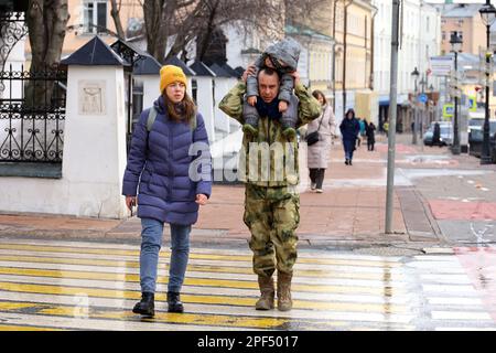 Couple with child crossing the city street by crosswalk. Father with sleeping kid sitting on his shoulders Stock Photo