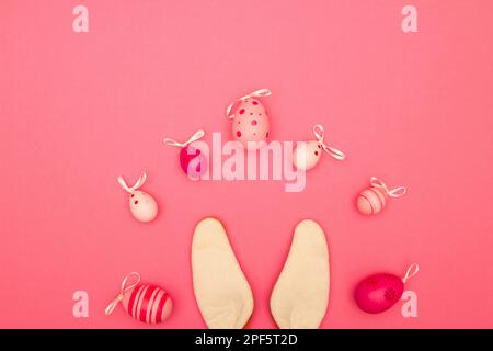 Celebrate Easter with a pink background that includes copy space, Easter eggs, and bunny ears Stock Photo