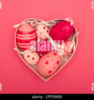 Easter eggs in the heart shaped box on pink background Stock Photo