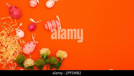 Red-Orange Easter background with flowers and Easter eggs creates a perfect space for copying Stock Photo