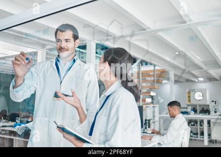 Using data to draw conclusions and interpret them. two young scientists brainstorming with notes on a glass screen in a lab. Stock Photo