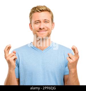 Finger and toes crossed. a handsome young man standing alone in the studio and feeling hopeful while crossing his fingers. Stock Photo