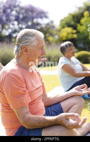 Happy diverse group of senior friends practicing yoga and meditating in garden Stock Photo