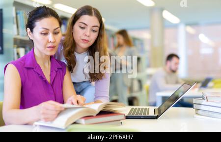 Two female colleagues working on joint project in library Stock Photo