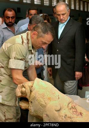 U.S. Marine Corps Col. Matthew Bogdanos, left, leads Iraqi opposition leader Ahmed Chalabi, right, on a tour of the national museum in Baghdad, Saturday, May 10, 2003. Bogdanos, an infantryman, scholar, amateur boxer and one-time waiter at his father's Greek restaurant, has found a case that draws on all his wide-ranging expertise - tracking down the looted treasures from Iraq's national museum. (AP Photo/Samir Mizban)