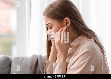 Young woman with ear plugs suffering from loud noise at home, closeup Stock Photo
