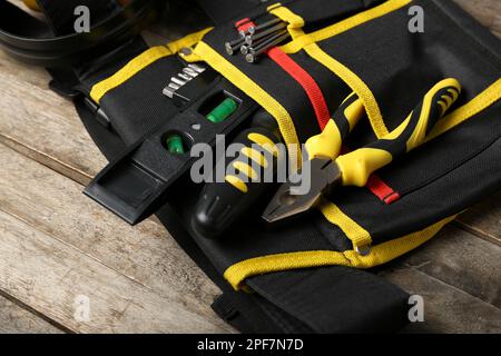 Pliers in belt with tools on wooden table Stock Photo