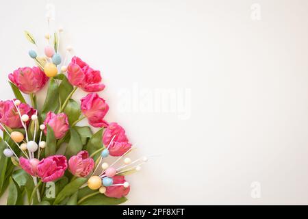 Border of pink parrot tulips and easter eggs on a white background with copy space Stock Photo