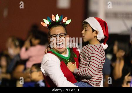 Matamoros, Tamaulipas, Mexico - Dicember 9, 2022: The Desfile de Navidad, Mother holding her child smiling at the camera Stock Photo