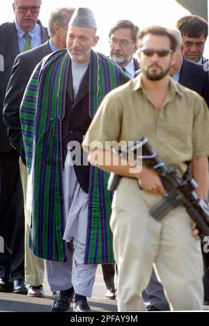 An armed bodyguard walks in front of Afghan President Hamid Karzai after leaving a plane on his way to a brief meeting with German Foreign Minister Joschka Fischer, after Karzai arrived at the U.S. Rhein Main Air Base, at the southern end of Frankfurt international airport, Germany, Sunday, Sept. 8, 2002. In his first trip since an attempt on his life three days ago, Karzai stopped over in Germany on his way to the United States where he will attend the U.N. General Assembly debate and ceremonies marking the anniversary of the Sept. 11 terrorist attacks. (AP Photo/Frank Rumpenhorst, Pool)