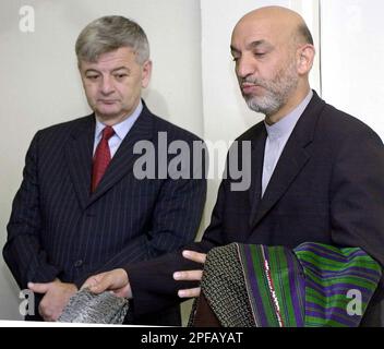 Afghan President Hamid Karzai, right, gestures after he was welcomed by German Foreign Minister Joschka Fischer, left, following his arrival at the U.S. Rhein Main Air Base, at the southern end of Frankfurt international airport, Germany, Sunday, Sept. 8, 2002. In his first trip since an attempt on his life three days ago, Karzai stopped over in Germany on his way to the United States where he will attend the U.N. General Assembly debate and ceremonies marking the anniversary of the Sept. 11 terroristattacks. (AP Photo/Pool/Oliver Berg)