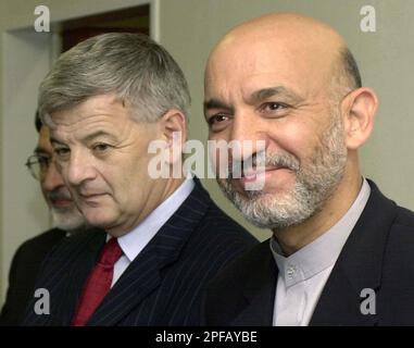 Afghan President Hamid Karzai, right, smiles after he was welcomed by German Foreign Minister Joschka Fischer, left, after he arrived at the U.S. Rhein Main Air Base, at the southern end of Frankfurt international airport, Germany, Sunday, Sept. 8, 2002. In his first trip since an attempt on his life three days ago, Karzai stopped over in Germany on his way to the United States where he will attend the U.N. General Assembly debate and ceremonies marking the anniversary of the Sept. 11 terrorist attacks. (AP Photo/Pool/Oliver Berg)