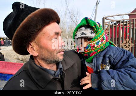 An Uyghur man with his grandchild at a colorful weekly livestock market in the outskirts of Kashgar, Xinjiang, China. Stock Photo