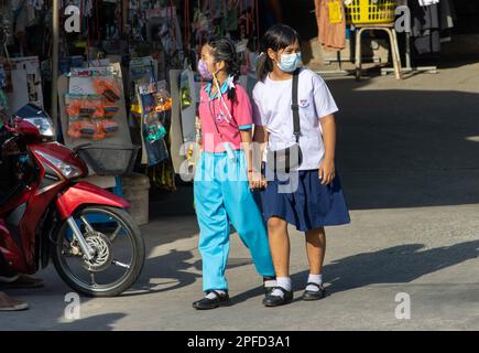 SAMUT PRAKAN, THAILAND, FEB 13 2023, A pair of girls in school uniforms are walking down the street holding hands Stock Photo