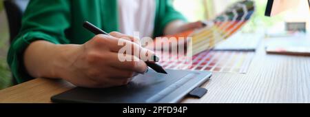 Designer draws sketches on graphics tablet and holds color palette. Working as graphic designer and photo editing Stock Photo