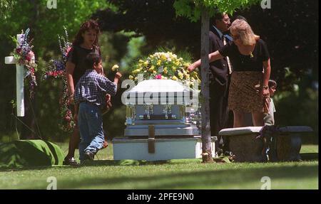 Family members leave flowers on the casket of Anthony Michael