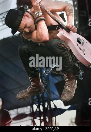 Rancid lead singer Tim Armstrong jumps while playing on the main