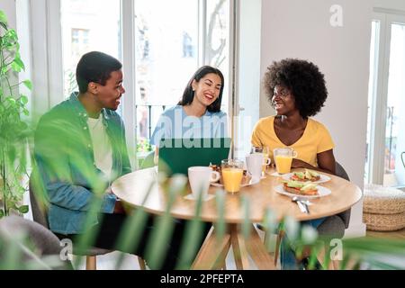 Multiethnic collegues working at home while eating pastries Stock Photo