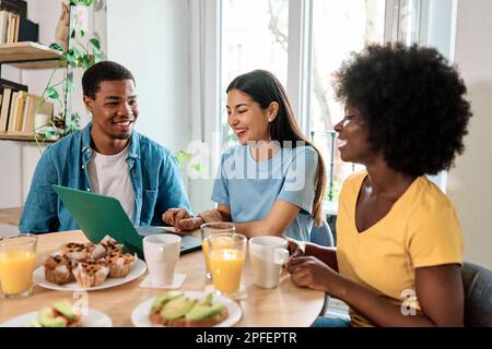 Friends using laptop while having breakfast at home Stock Photo