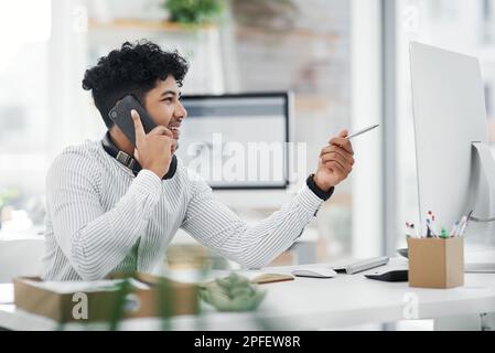 Im looking at your email right now. a young businessman talking on a cellphone while working on a computer in an office. Stock Photo
