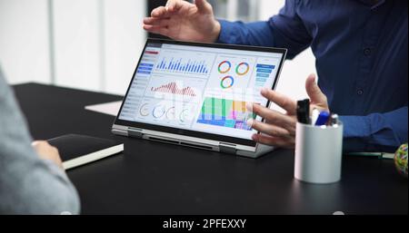 Two Businesspeople Analyzing Financial Graph On Laptop Stock Photo
