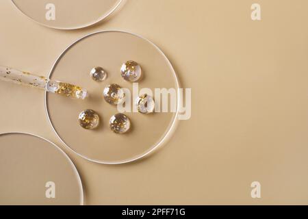 Samples of gel cosmetic products with gold in a Petri dish on beige background Stock Photo